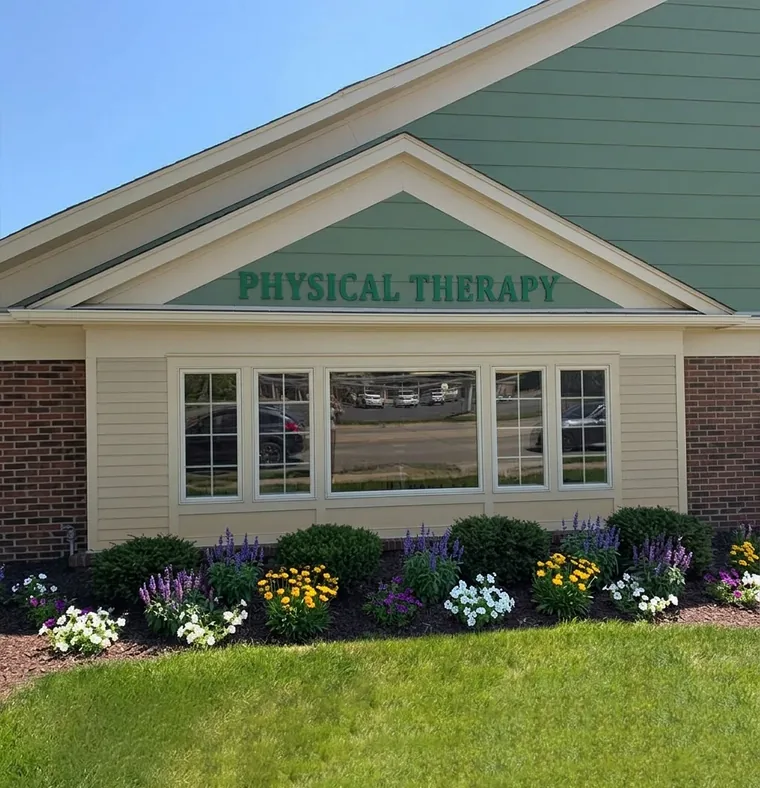 The front of a physical therapy clinic with flower beds along the building