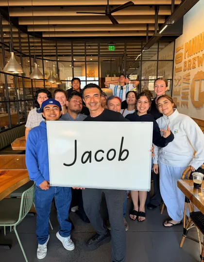 A café owner and his team holding up a sign with a customer's name on it